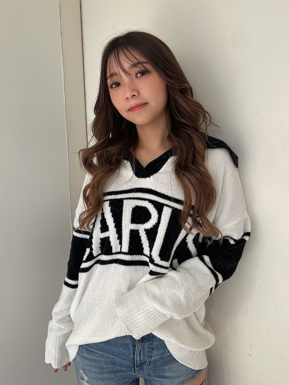 ホワイト系のニット/セーター、ブルー系のデニムパンツ、ホワイト系のパンプスを着用したレディースの秋コーディネートの4枚目の写真