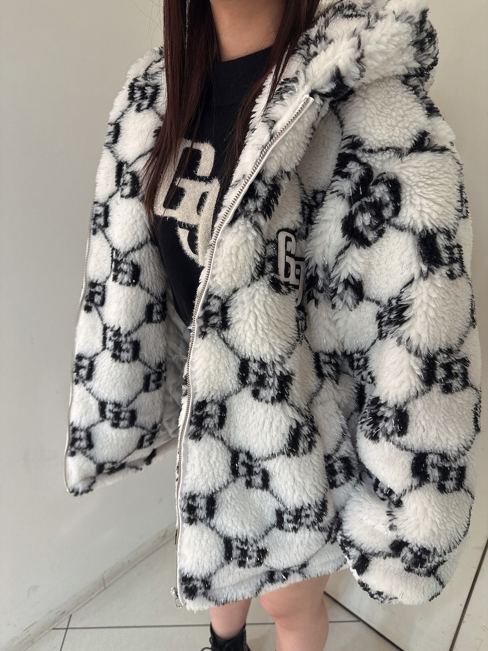 ホワイト系のブルゾン、ブラック系のスカート、ブラック系のブーツを着用したレディースの秋コーディネートの7枚目の写真