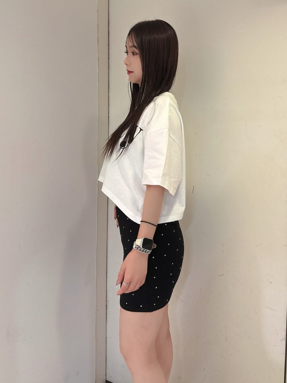 ブラック系のスカート、ホワイト系のTシャツ/カットソー、ブラック系のサンダルを着用したレディースの夏コーディネートの5枚目の写真