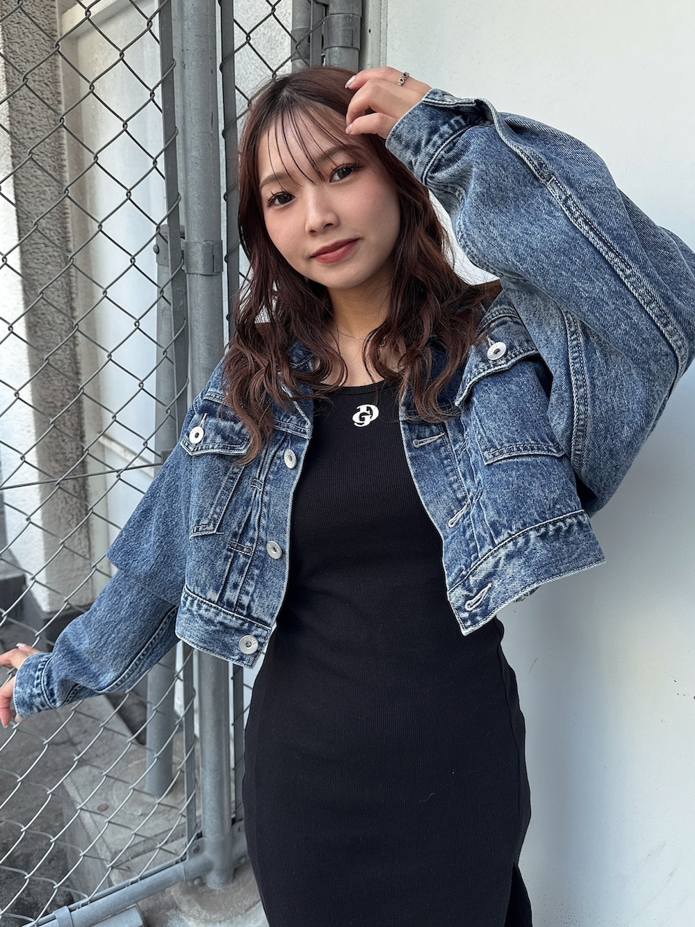 ブラック系のワンピース、ホワイト系のパンプス、ブルー系のデニムジャケットを着用したレディースの春コーディネートの5枚目の写真