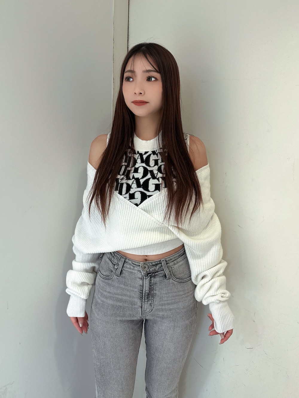 グレー系のデニムパンツ、ブラック系のブーツ、ホワイト系のニット/セーターを着用したレディースの秋コーディネートの4枚目の写真