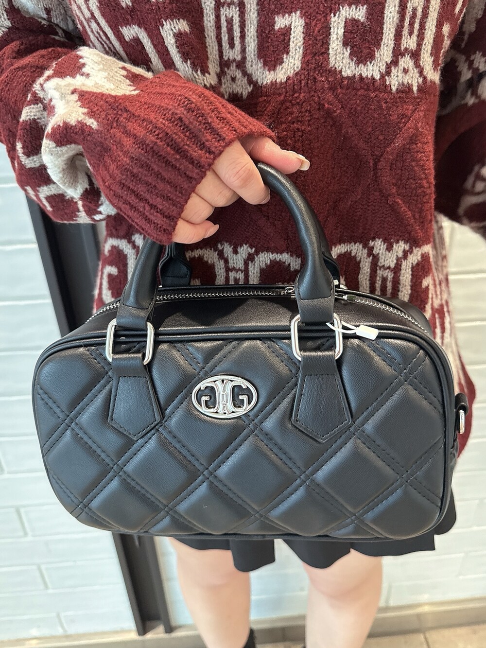 レッド系のニット/セーター、ブラック系のスカート、ブラック系のハンドバッグを着用したレディースの冬コーディネートの8枚目の写真