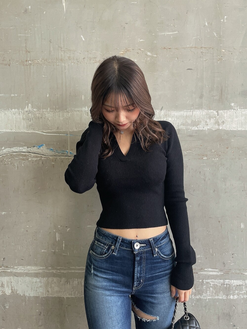 ブラック系のニット/セーター、ブラック系のチェスターコート、ブルー系のデニムパンツを着用したレディースの冬コーディネートの4枚目の写真