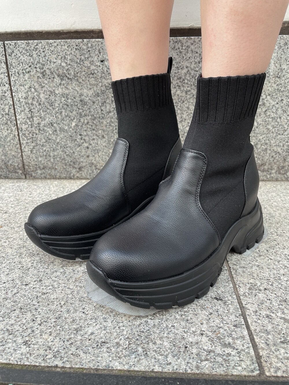 ブラック系のハンドバッグ、ブラック系のブーツ、ブラック系のワンピースを着用したレディースの冬コーディネートの7枚目の写真