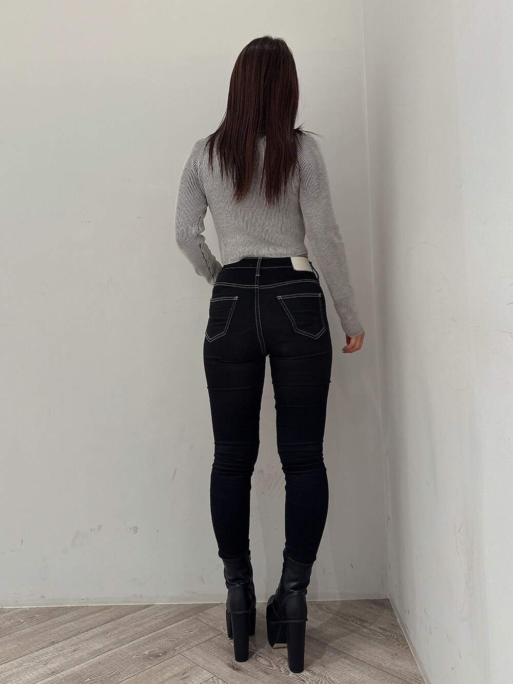 ブラック系のニット/セーター、ブラック系のデニムパンツ、ブラック系のブーツを着用したレディースの夏コーディネートの3枚目の写真