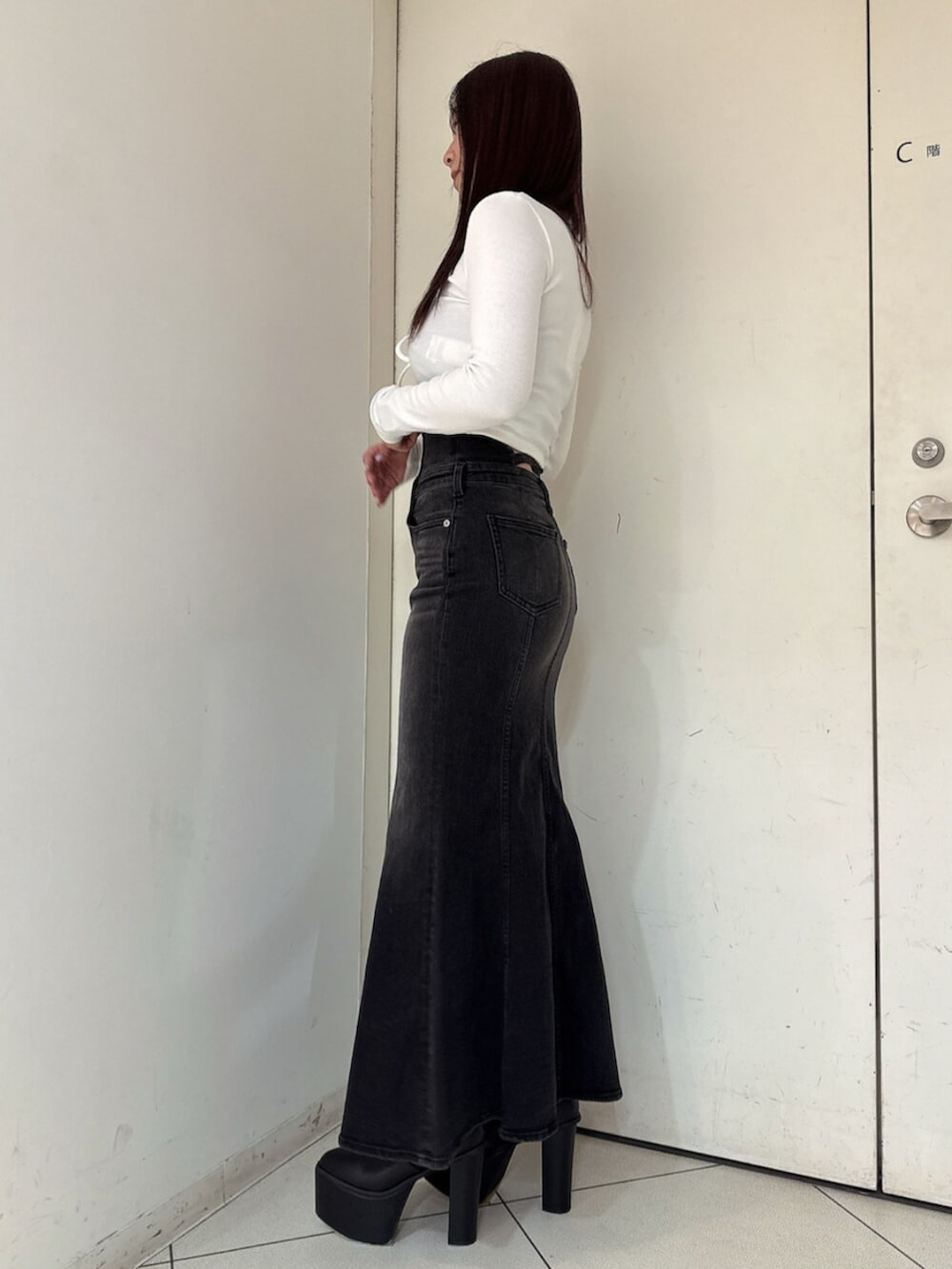 ブラック系のブーツ、ホワイト系のTシャツ/カットソー、ブラック系のデニムスカートを着用したレディースの秋コーディネートの2枚目の写真