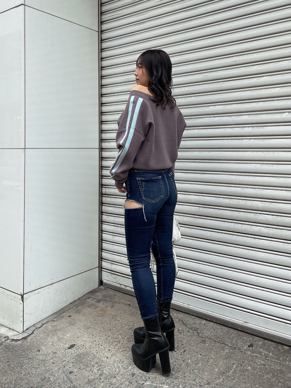 グレー系のニット/セーター、ブルー系のデニムパンツ、ブラック系のブーツを着用したレディースの冬コーディネートの2枚目の写真