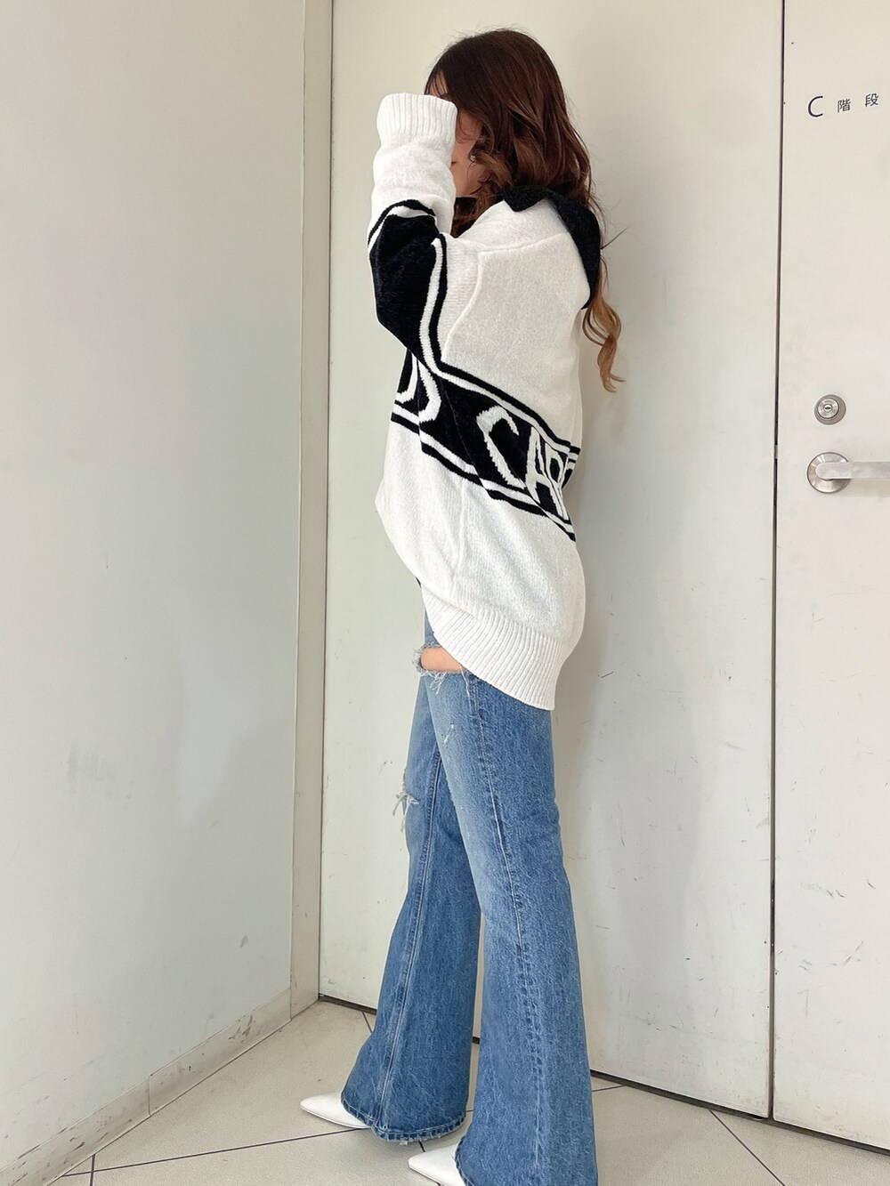 ホワイト系のニット/セーター、ブルー系のデニムパンツ、ホワイト系のパンプスを着用したレディースの秋コーディネートの2枚目の写真