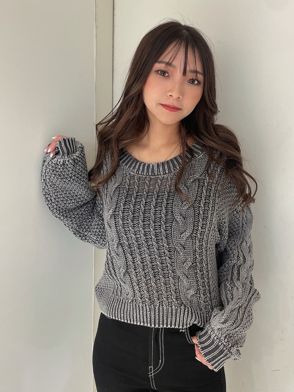 グレー系のニット/セーター、ブラック系のデニムパンツ、ホワイト系のパンプスを着用したレディースの夏コーディネートの6枚目の写真