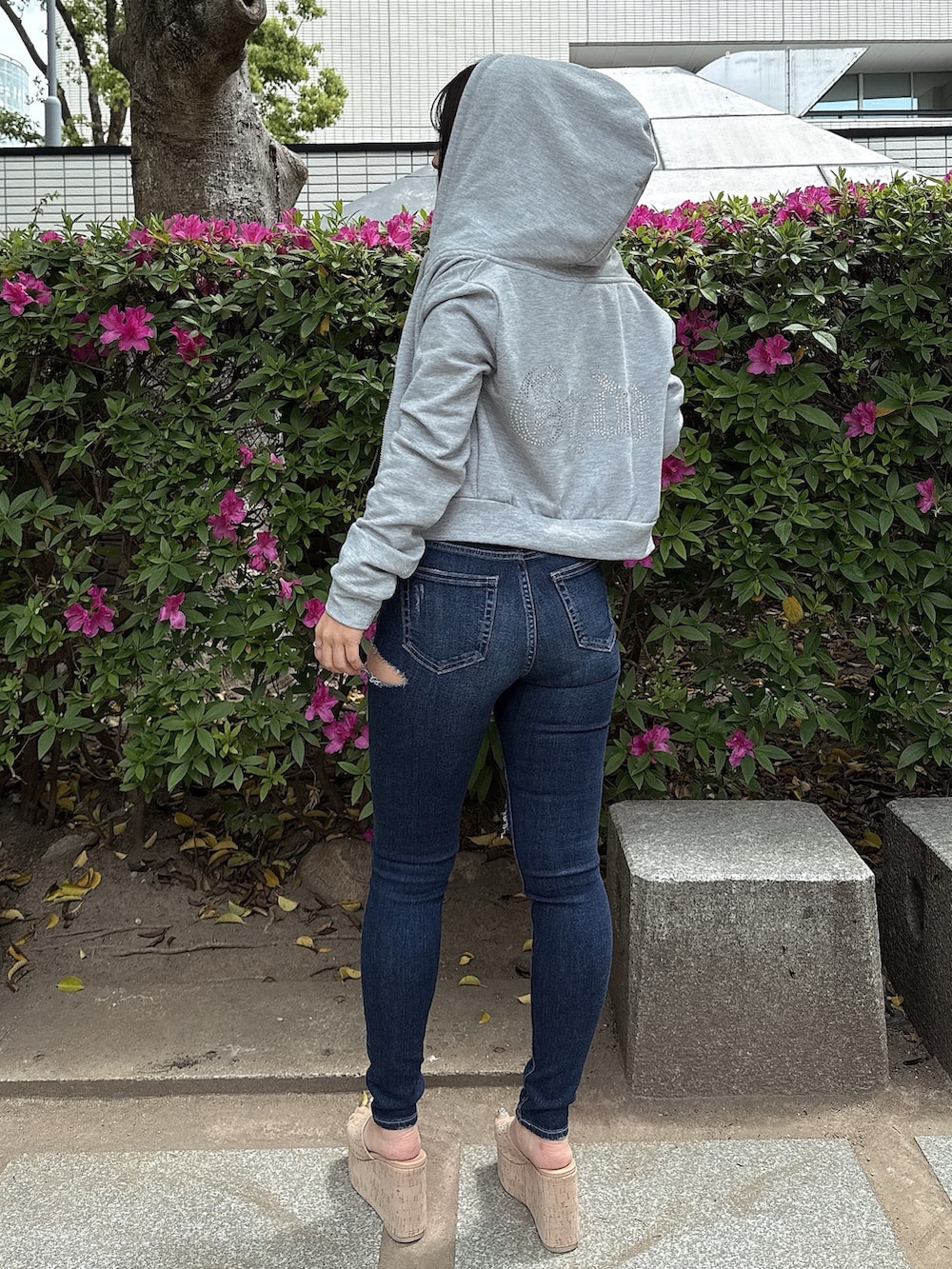 グレー系のパーカー、ブルー系のデニムパンツ、ホワイト系のサンダルを着用したレディースの春コーディネートの3枚目の写真