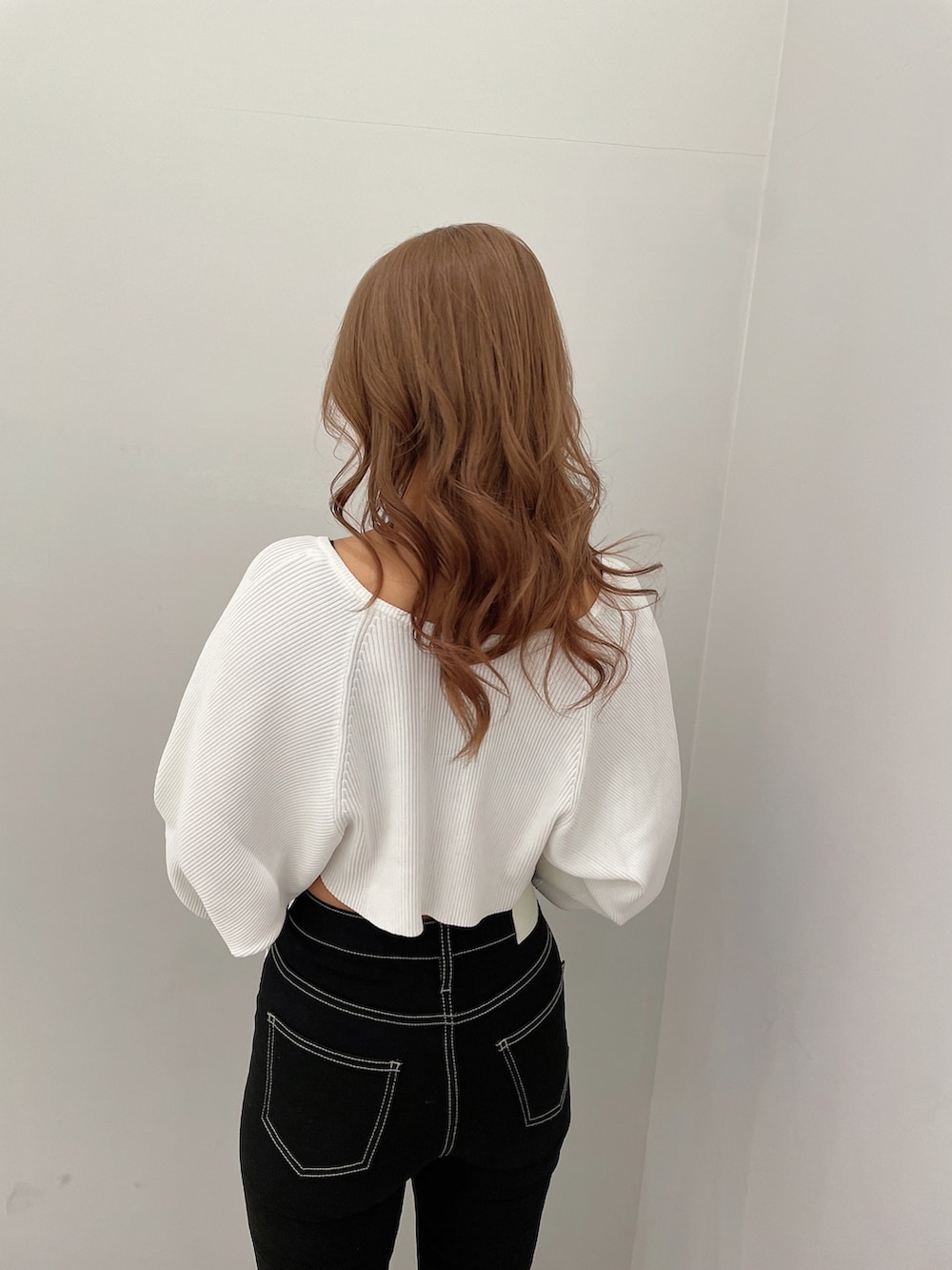 ブラック系のデニムパンツ、ブラック系のハンドバッグ、ホワイト系のパンプスを着用したレディースの春コーディネートの5枚目の写真