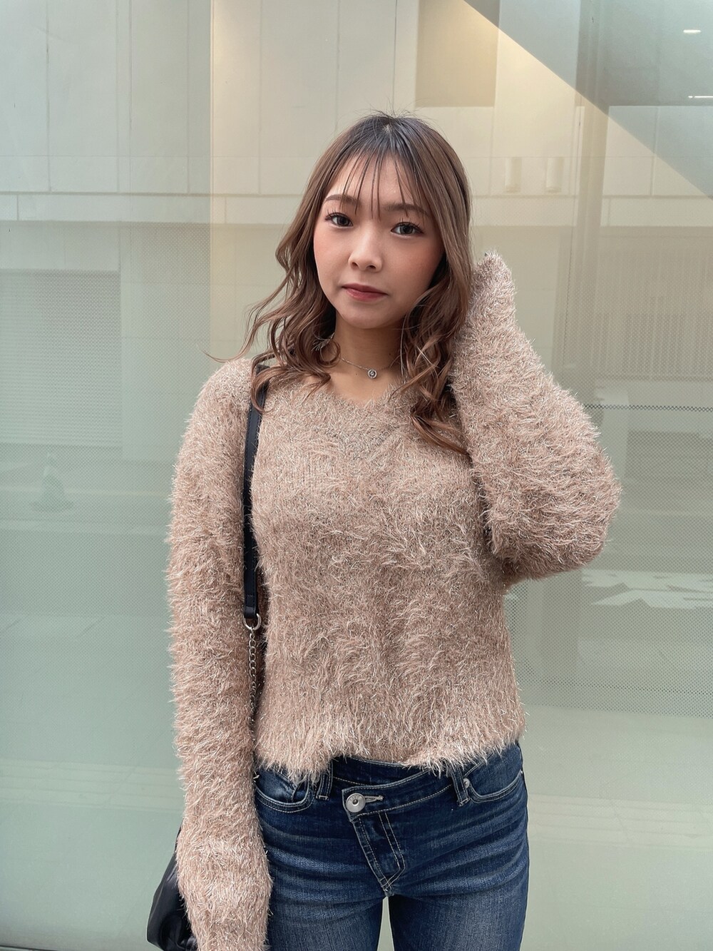 ブラック系のダウンジャケット/コート、ベージュ系のニット/セーター、ブルー系のデニムパンツを着用したレディースの秋コーディネートの5枚目の写真