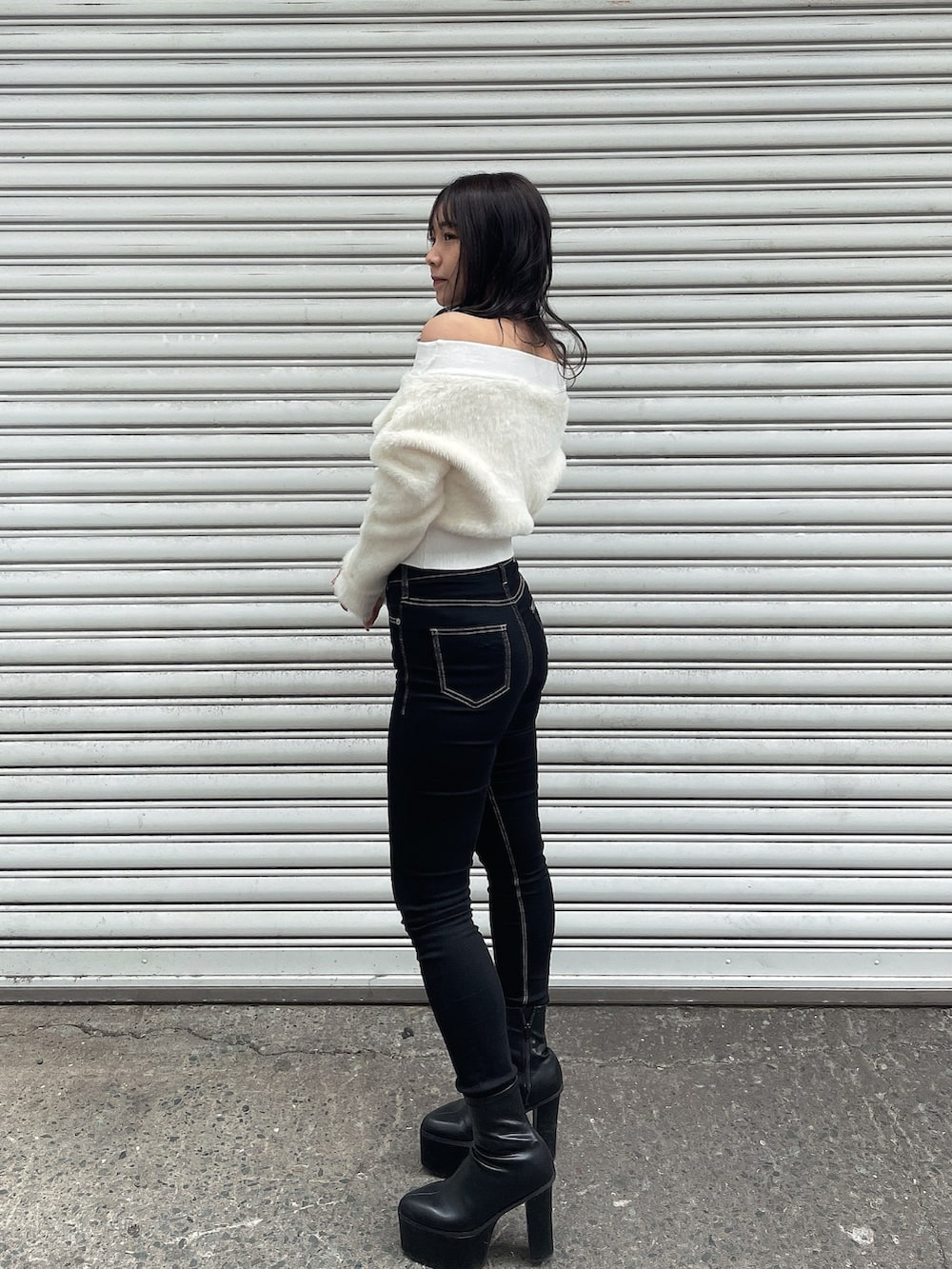 ブラック系のダウンジャケット/コート、ホワイト系のニット/セーター、ブラック系のデニムパンツを着用したレディースの冬コーディネートの6枚目の写真