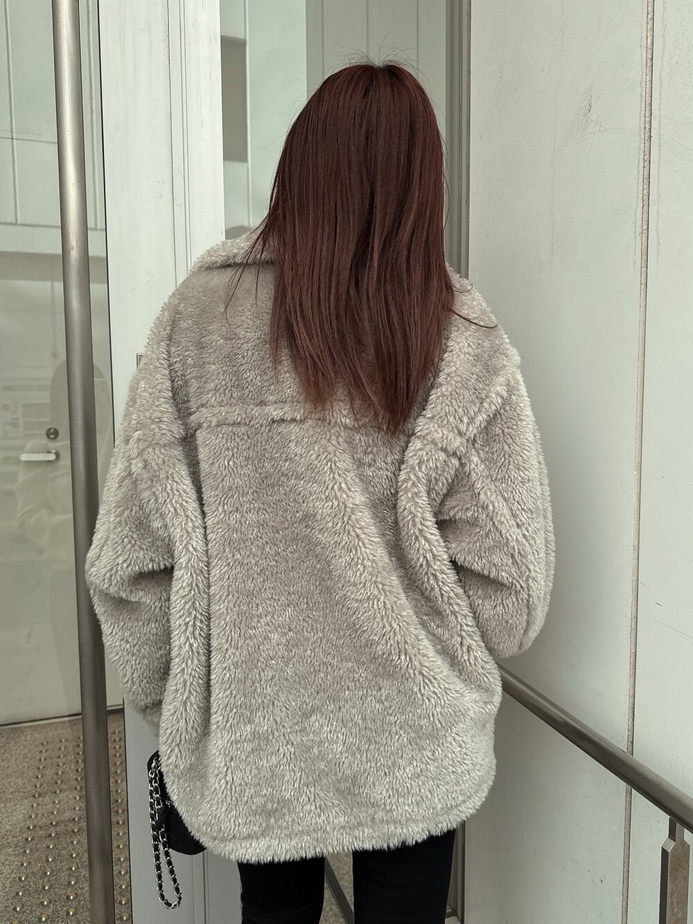 グレー系のブルゾン、ブラック系のデニムパンツ、ブラック系のブーツを着用したレディースの冬コーディネートの6枚目の写真