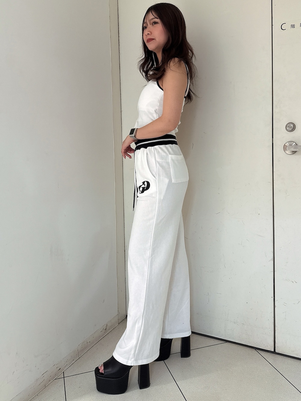 ブラック系のサンダル、ホワイト系のスウェットパンツ、ホワイト系のキャミソールを着用したレディースの夏コーディネートの2枚目の写真