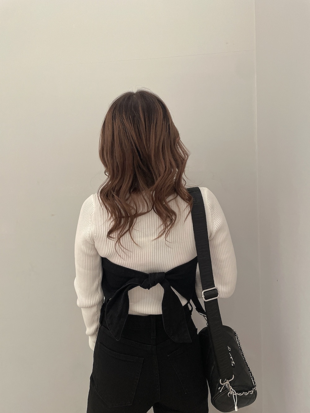 ホワイト系のニット/セーター、ブラック系のサロペット/オーバーオール、ブラック系のハンドバッグを着用したレディースの冬コーディネートの5枚目の写真