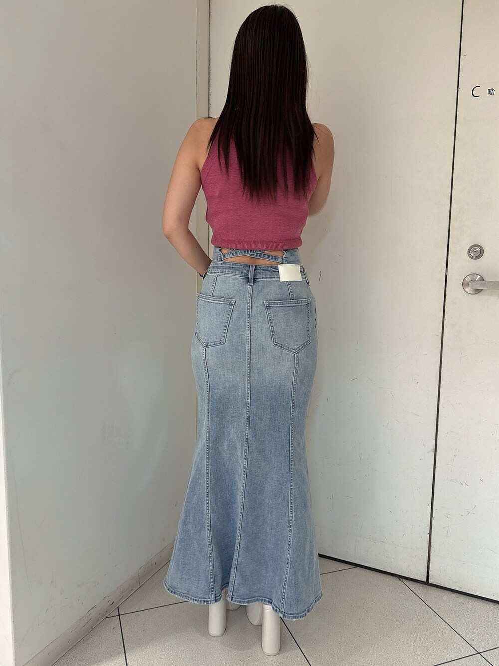 ピンク系のニット/セーター、ブルー系のデニムスカート、ホワイト系のサンダルを着用したレディースの夏コーディネートの3枚目の写真