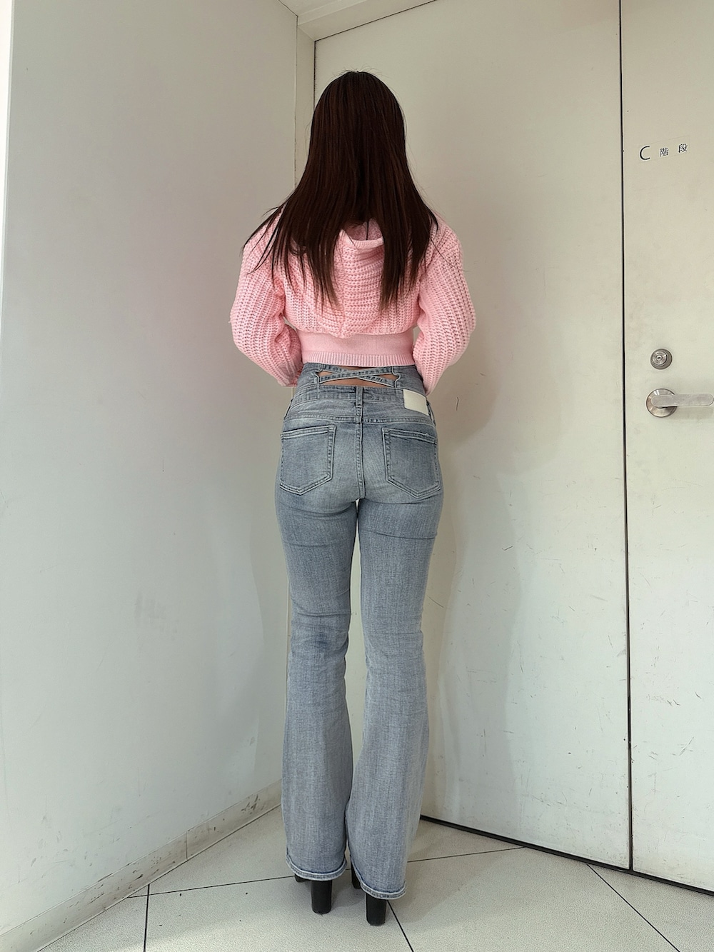 ブルー系のデニムパンツ、ピンク系のニット/セーター、ブラック系のブーツを着用したレディースの冬コーディネートの3枚目の写真