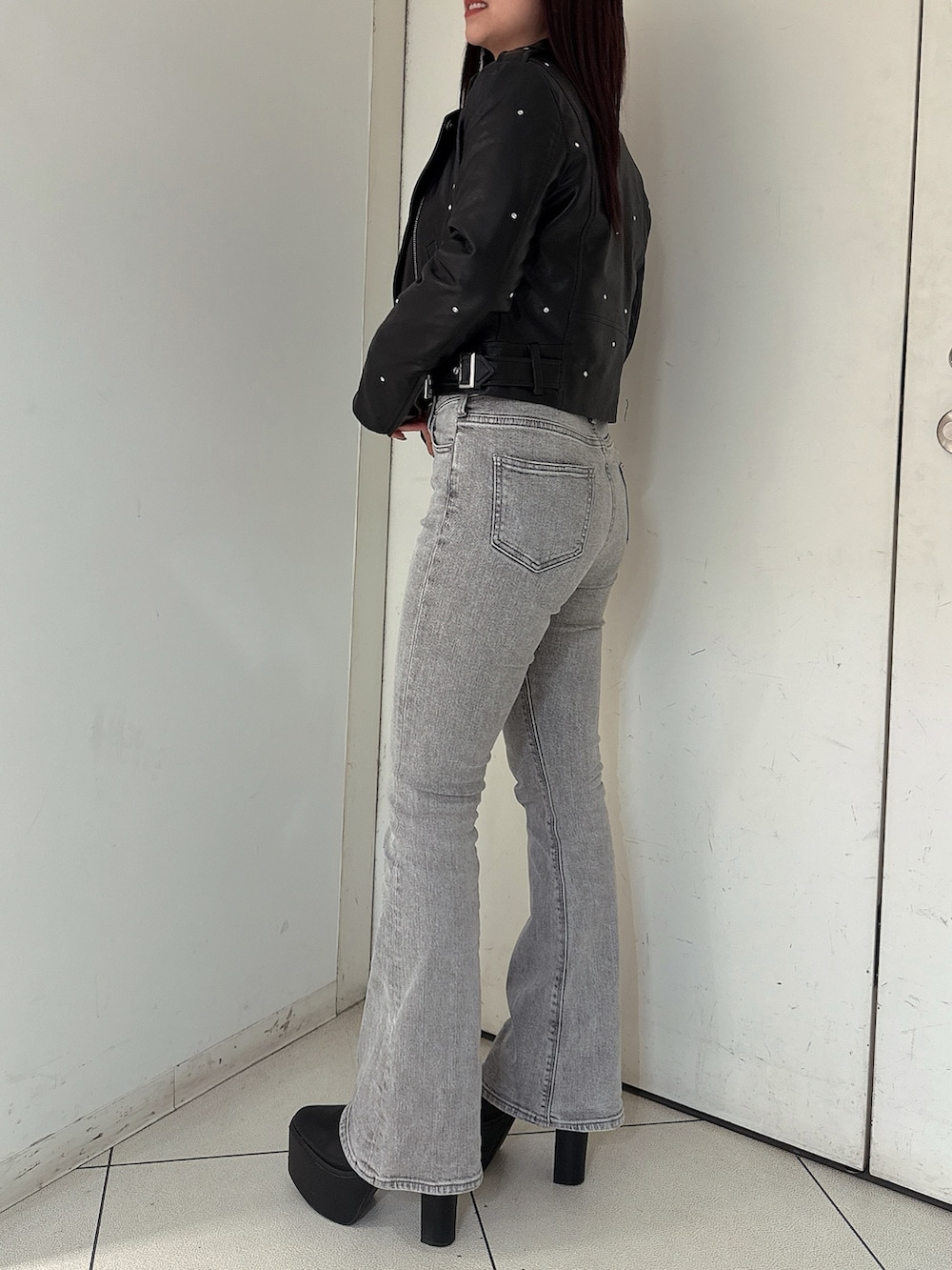 グレー系のデニムパンツ、ブラック系のブーツ、ブラック系のライダースジャケットを着用したレディースの夏コーディネートの2枚目の写真