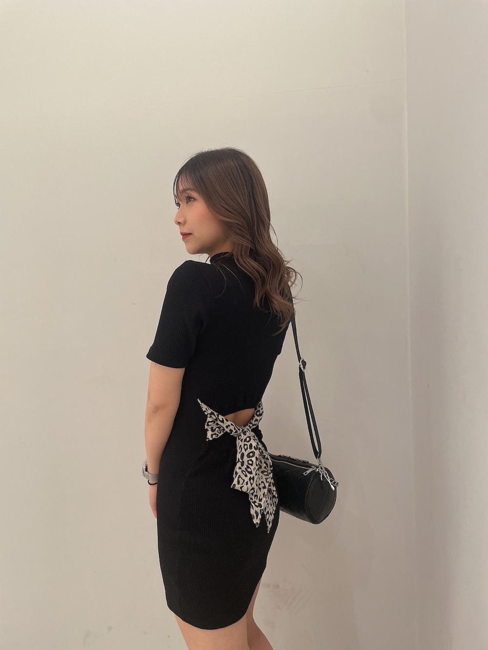 ブラック系のハンドバッグ、ブラック系のブーツ、ブラック系のワンピースを着用したレディースの冬コーディネートの5枚目の写真