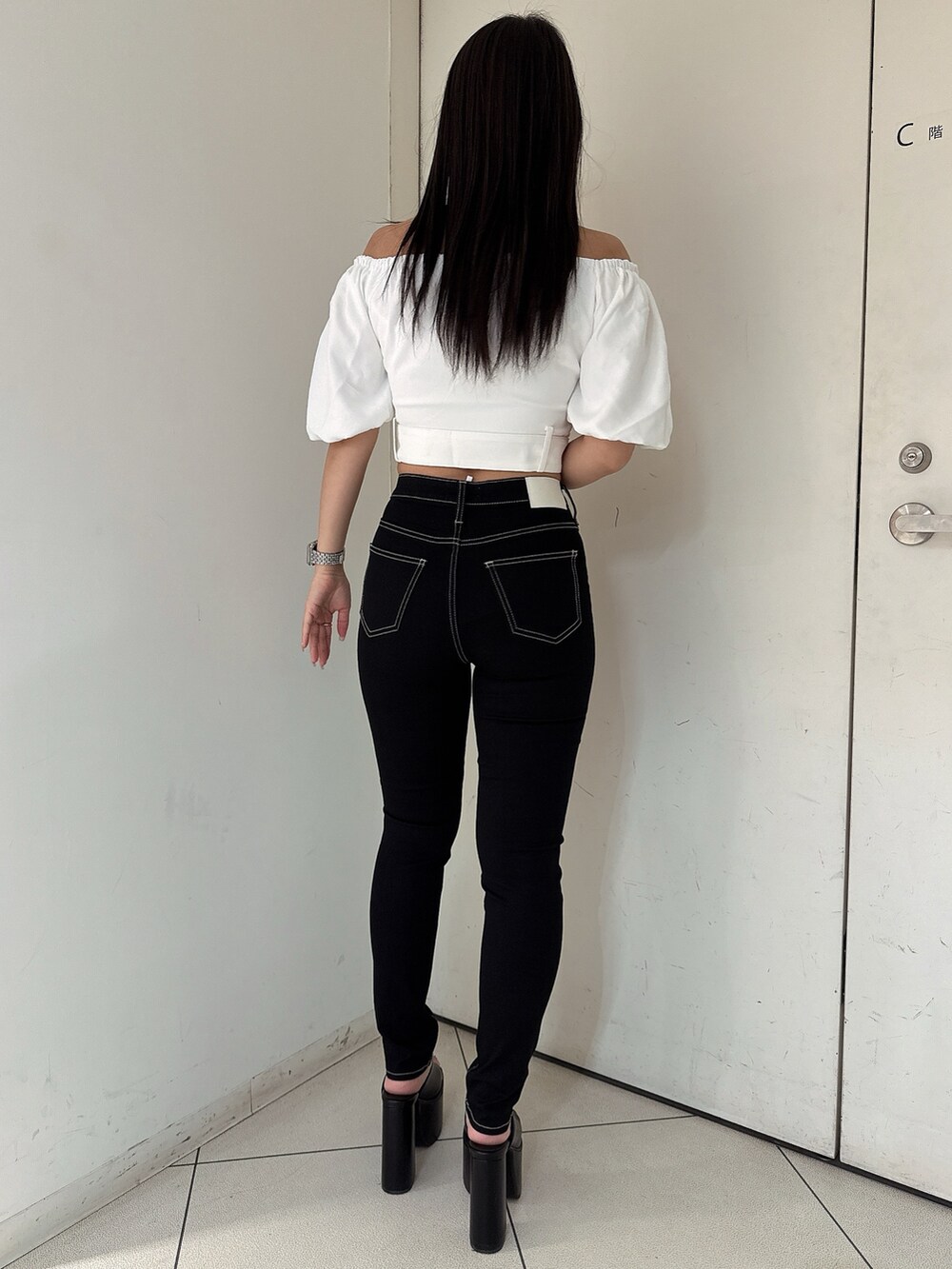 ブラック系のデニムパンツ、ブラック系のサンダル、ホワイト系のシャツ/ブラウスを着用したレディースの夏コーディネートの3枚目の写真