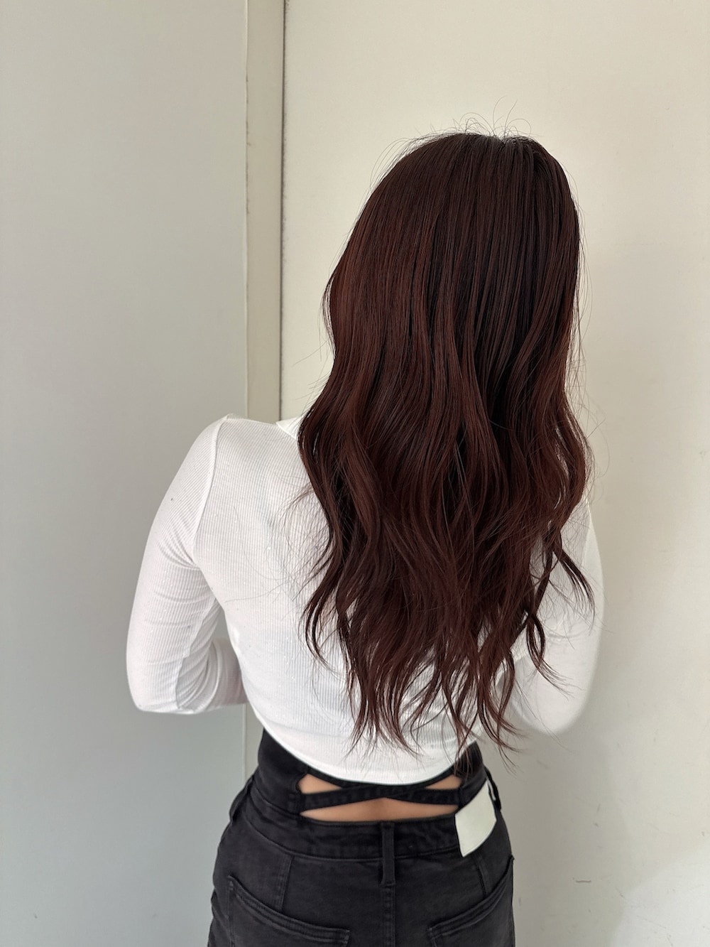 ブラック系のデニムスカート、ブラック系のTシャツ/カットソー、ホワイト系のパンプスを着用したレディースの秋コーディネートの6枚目の写真