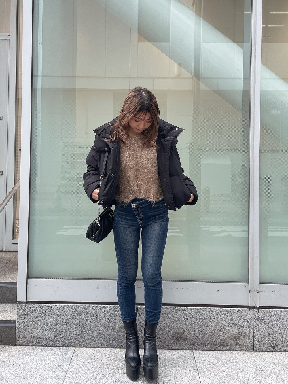 ブラック系のダウンジャケット/コート、ベージュ系のニット/セーター、ブルー系のデニムパンツを着用したレディースの秋コーディネートの2枚目の写真