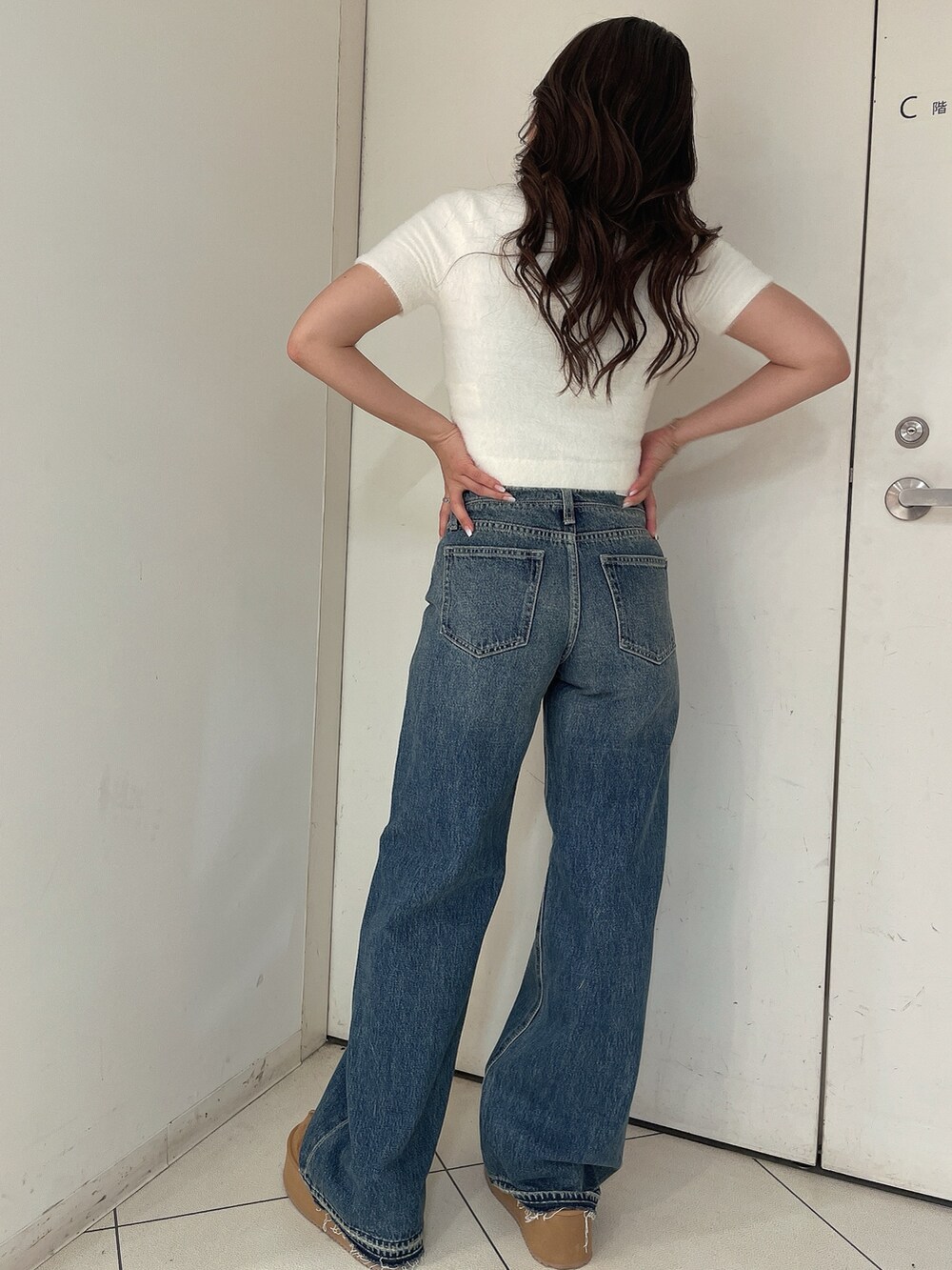 ホワイト系のニット/セーター、ブルー系のデニムパンツ、ベージュ系のスリッポンを着用したレディースの夏コーディネートの3枚目の写真