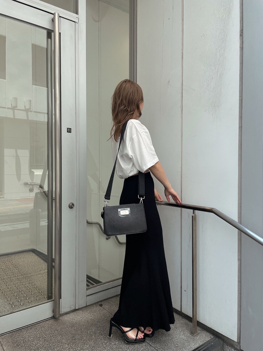 ブラック系のスカート、ブラック系のハンドバッグ、ホワイト系のTシャツ/カットソーを着用したレディースの夏コーディネートの3枚目の写真