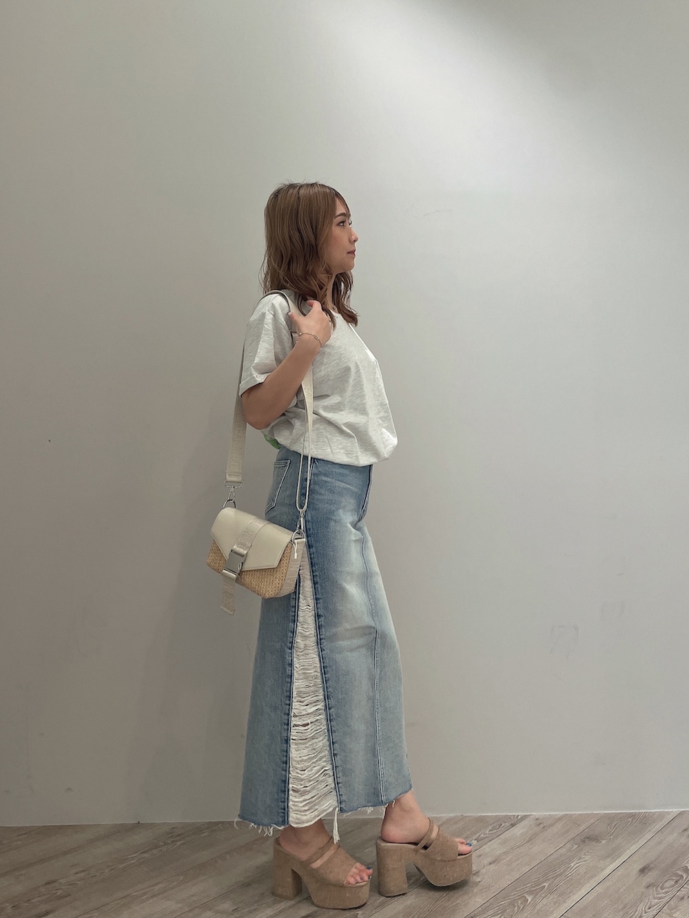 ホワイト系のTシャツ/カットソー、ブルー系のデニムスカート、ホワイト系のサンダルを着用したレディースの春コーディネートの3枚目の写真