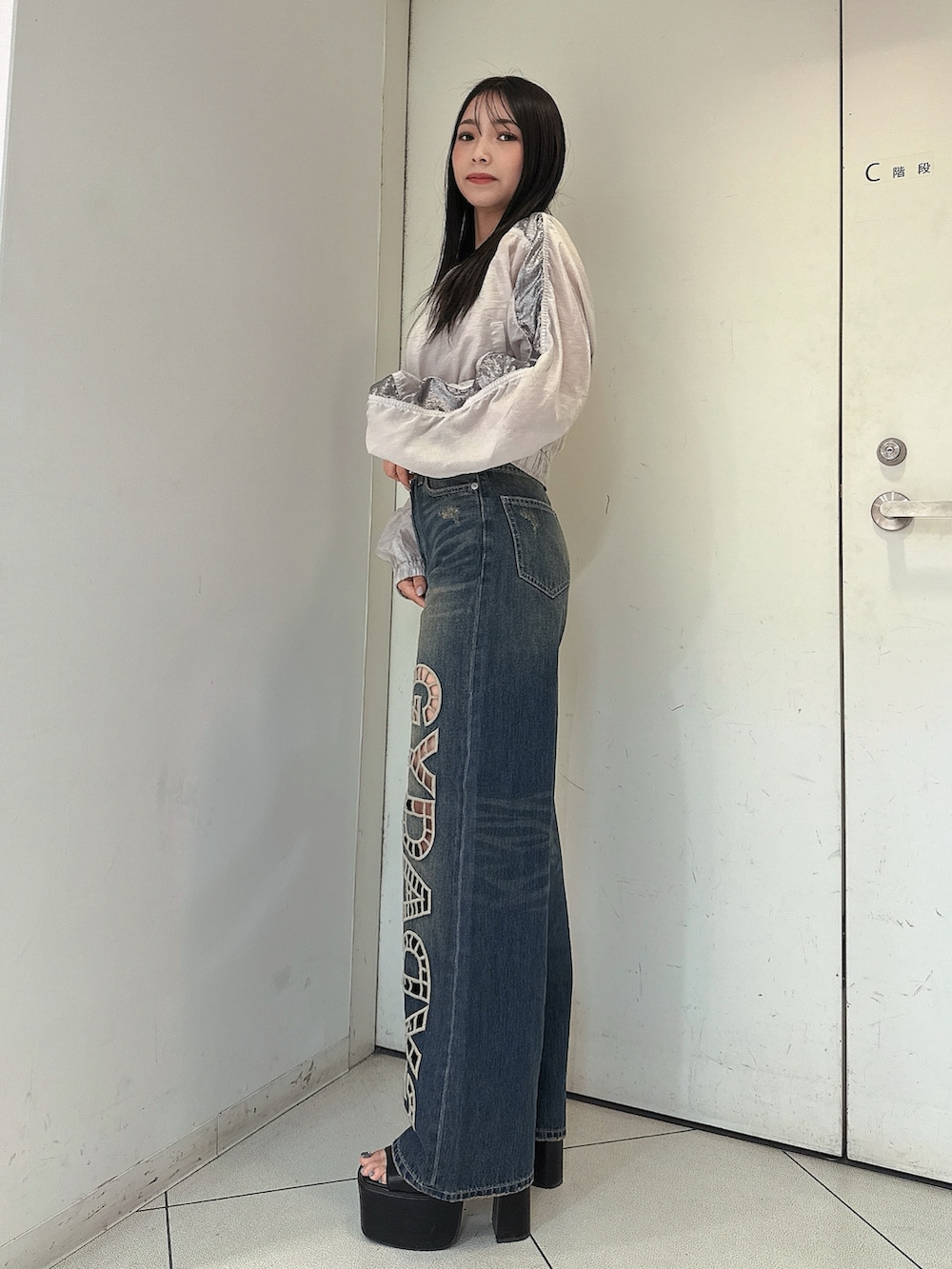 ブルー系のデニムパンツ、ホワイト系のキャミソール、ホワイト系のブルゾンを着用したレディースの春コーディネートの2枚目の写真