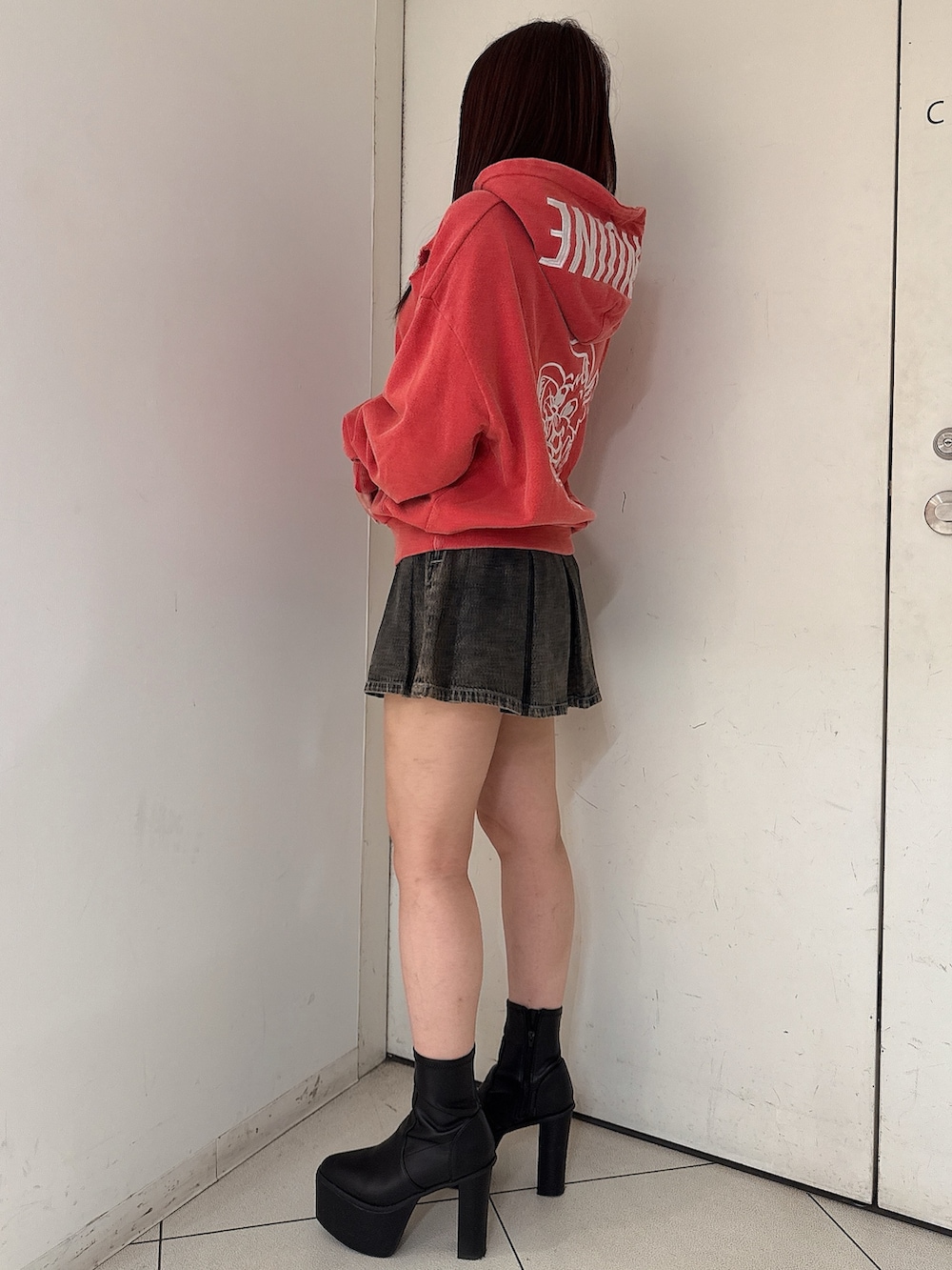 レッド系のパーカー、その他のデニムスカート、ブラック系のブーツを着用したレディースの秋コーディネートの2枚目の写真