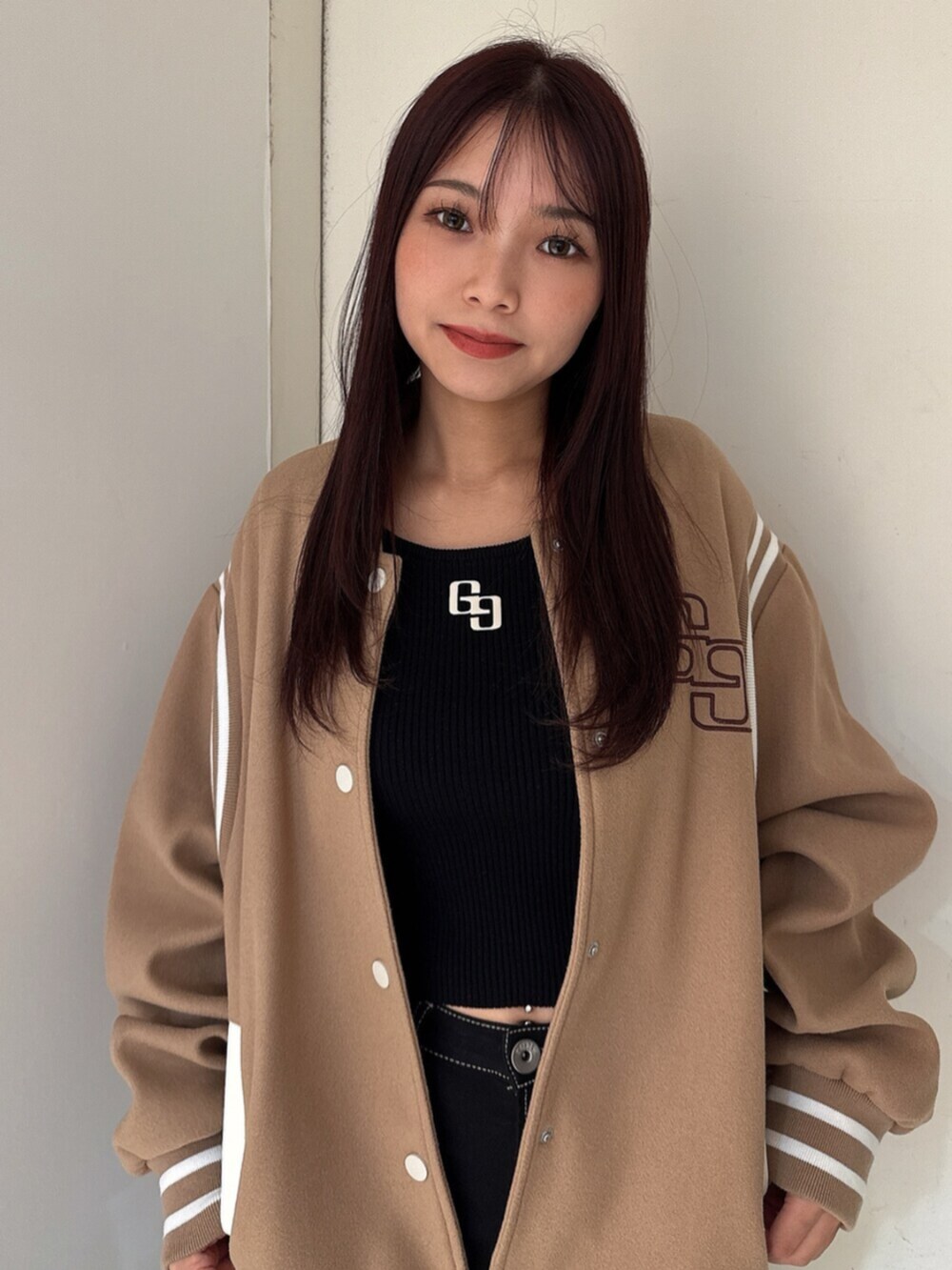 ブラック系のデニムパンツ、ブラック系のニット/セーター、ベージュ系のスタジャンを着用したレディースの秋コーディネートの4枚目の写真