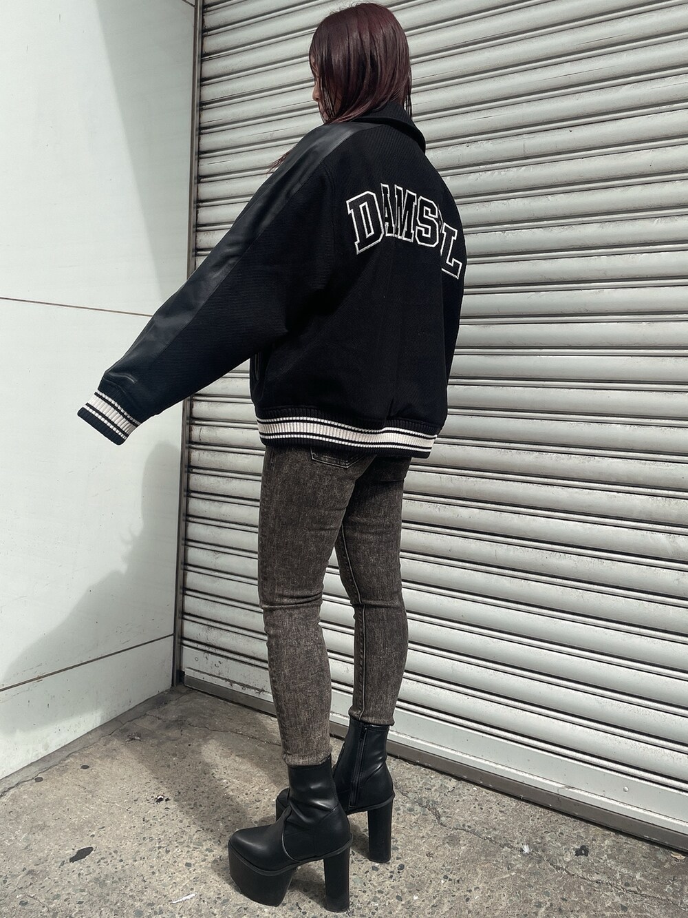 ブラック系のスタジャン、ブラック系のニット/セーター、ブラック系のデニムパンツを着用したレディースの秋コーディネートの2枚目の写真