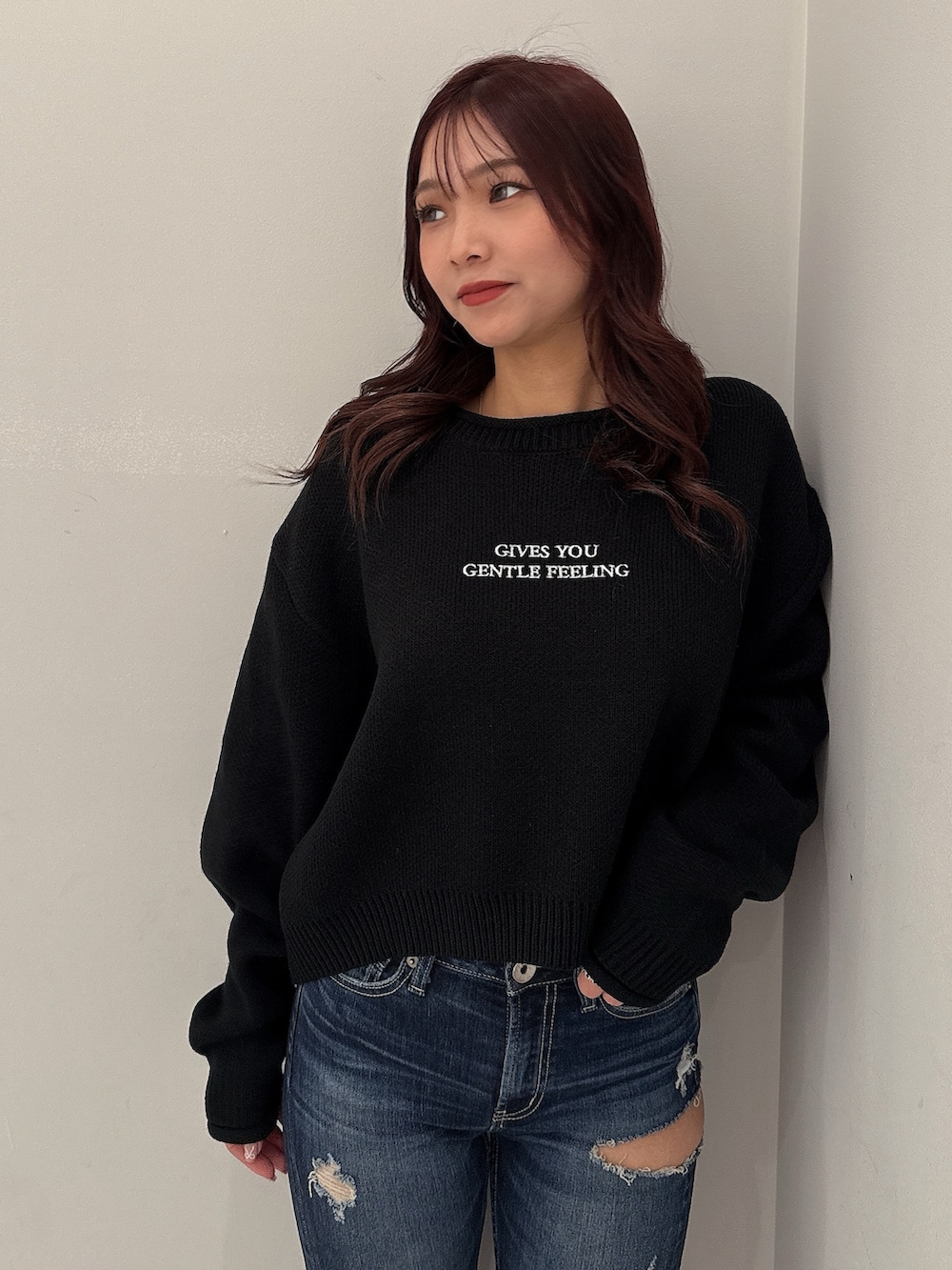 ブラック系のニット/セーター、ブルー系のデニムパンツ、ブラック系のブーツを着用したレディースの秋コーディネートの4枚目の写真