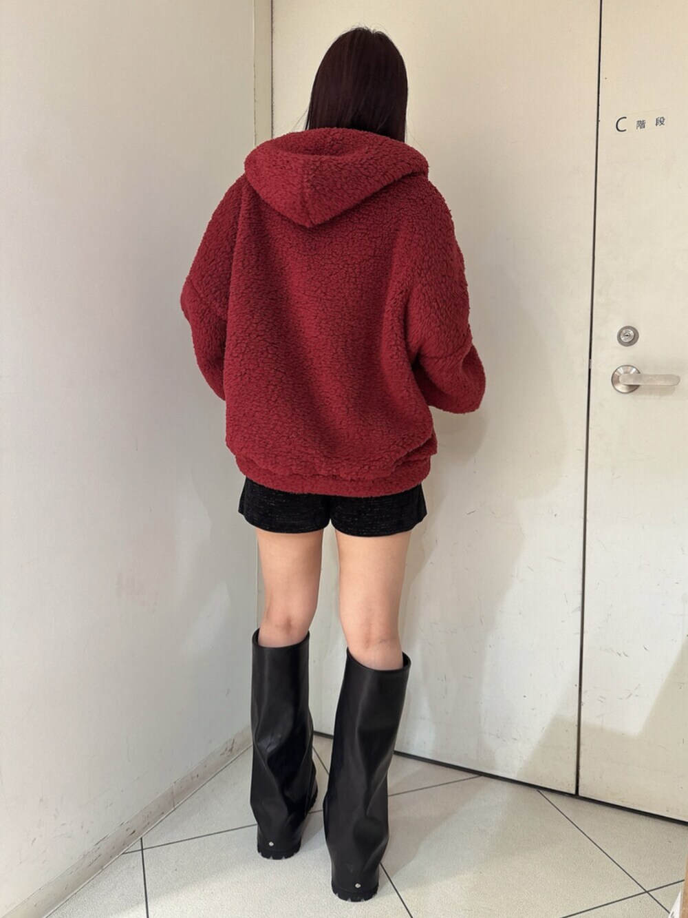 ブラック系のブーツ、レッド系のパーカー、ブラック系のその他パンツを着用したレディースの秋コーディネートの3枚目の写真