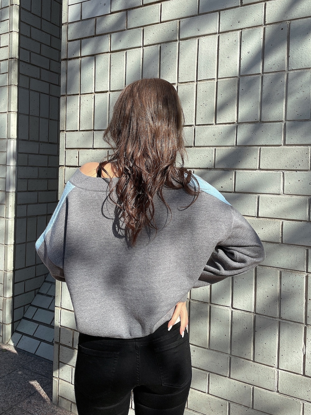 グレー系のニット/セーター、ブラック系のキャミソール、ブラック系のデニムパンツを着用したレディースの冬コーディネートの5枚目の写真