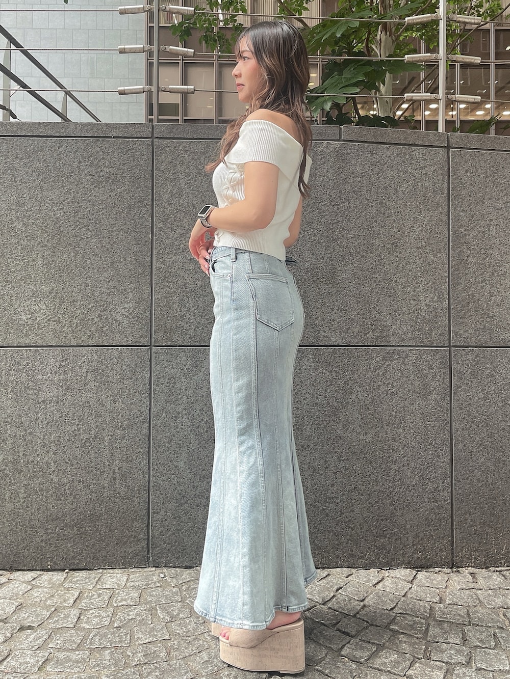 ブルー系のデニムスカート、ホワイト系のサンダル、ホワイト系のニット/セーターを着用したレディースの夏コーディネートの2枚目の写真