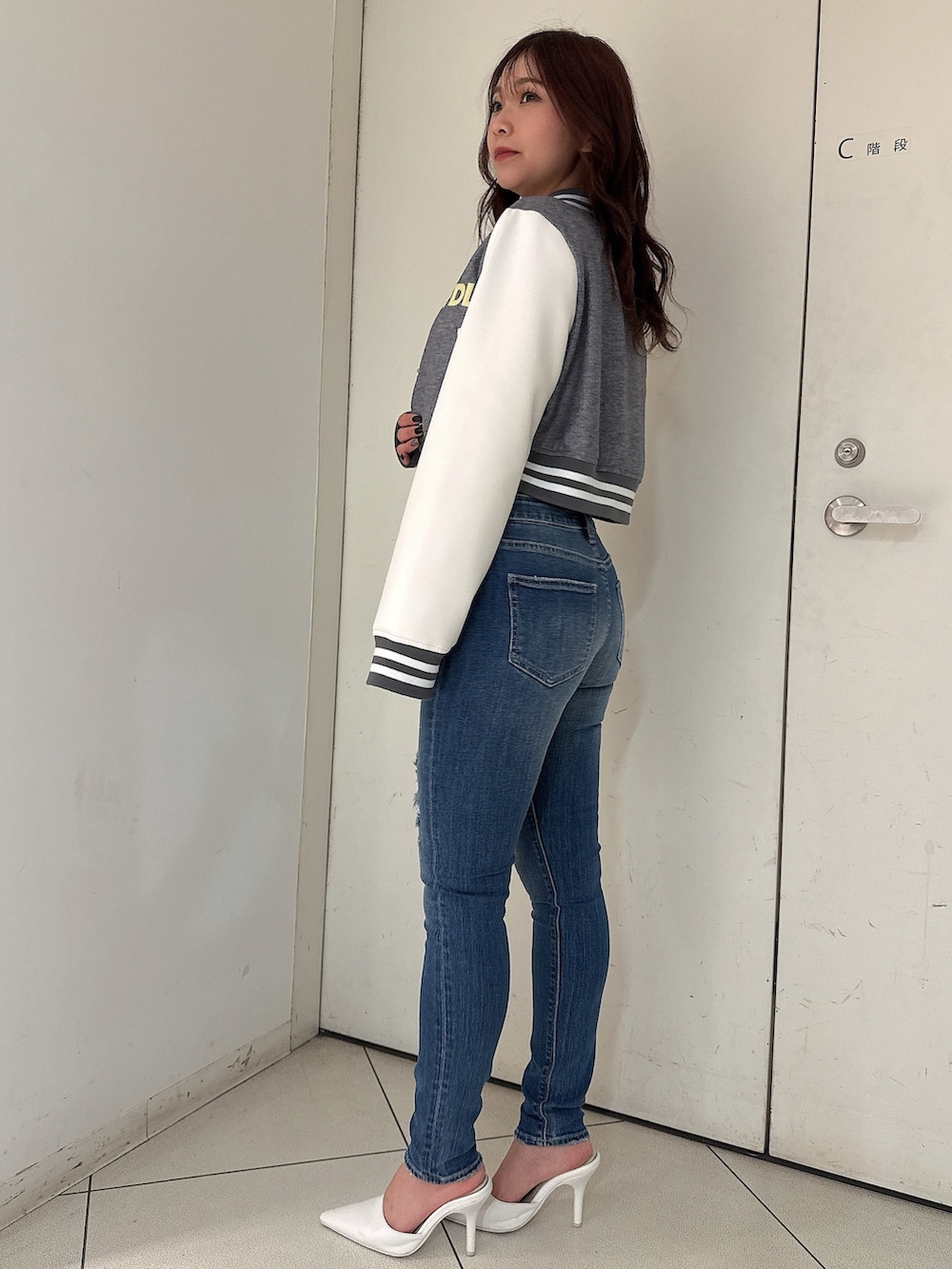 グレー系のニット/セーター、ブルー系のデニムパンツ、ホワイト系のパンプスを着用したレディースの冬コーディネートの2枚目の写真