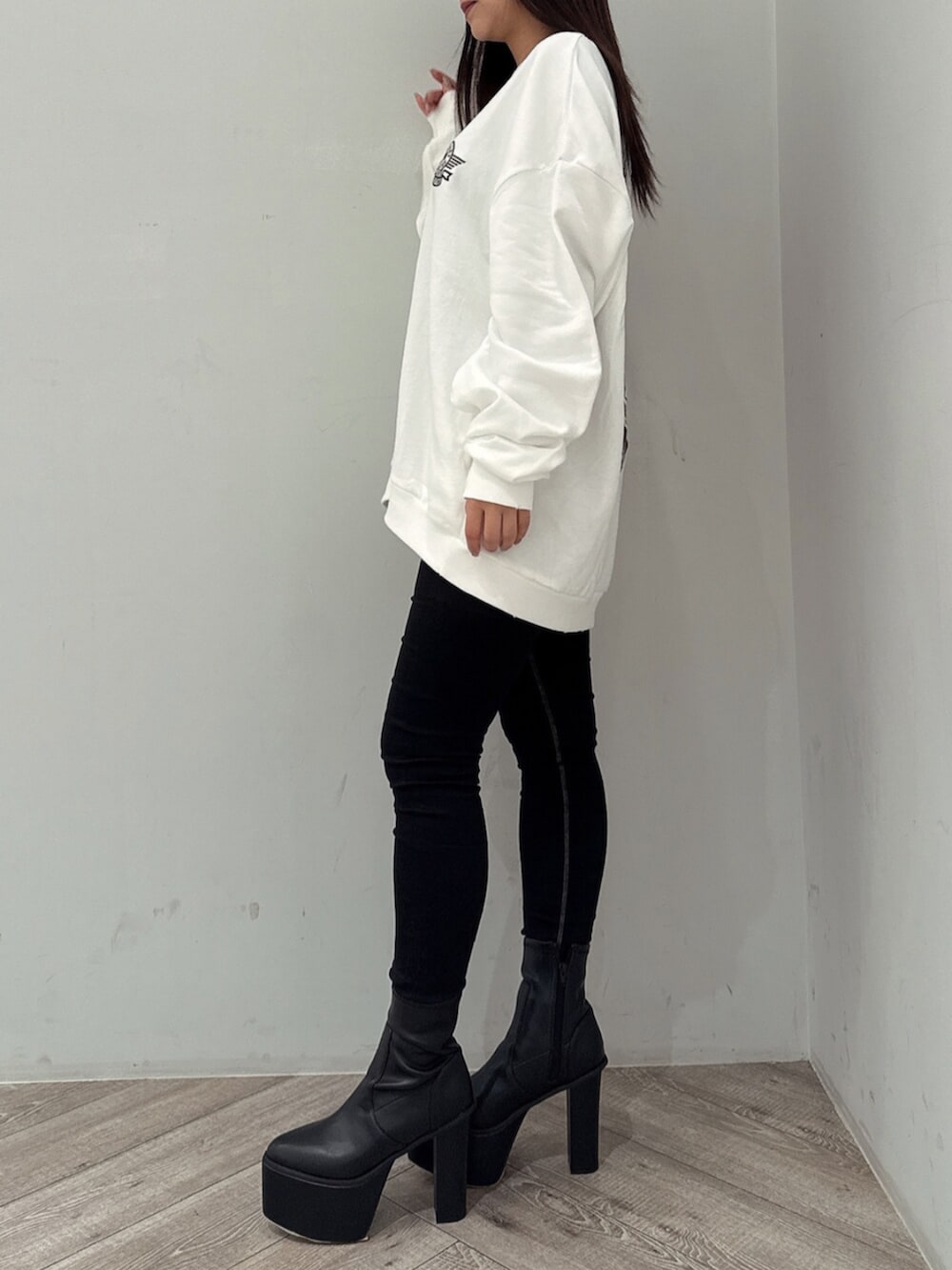 ブラック系のデニムパンツ、ホワイト系のスウェット、ブラック系のブーツを着用したレディースの夏コーディネートの2枚目の写真