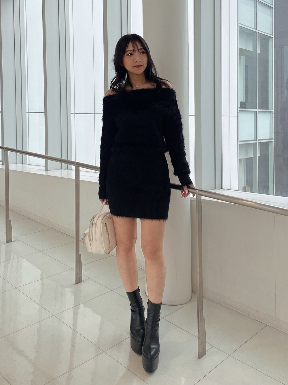 ブラック系のダウンジャケット/コート、ブラック系のワンピース、ホワイト系のバックパック/リュックを着用したレディースの冬コーディネートの7枚目の写真