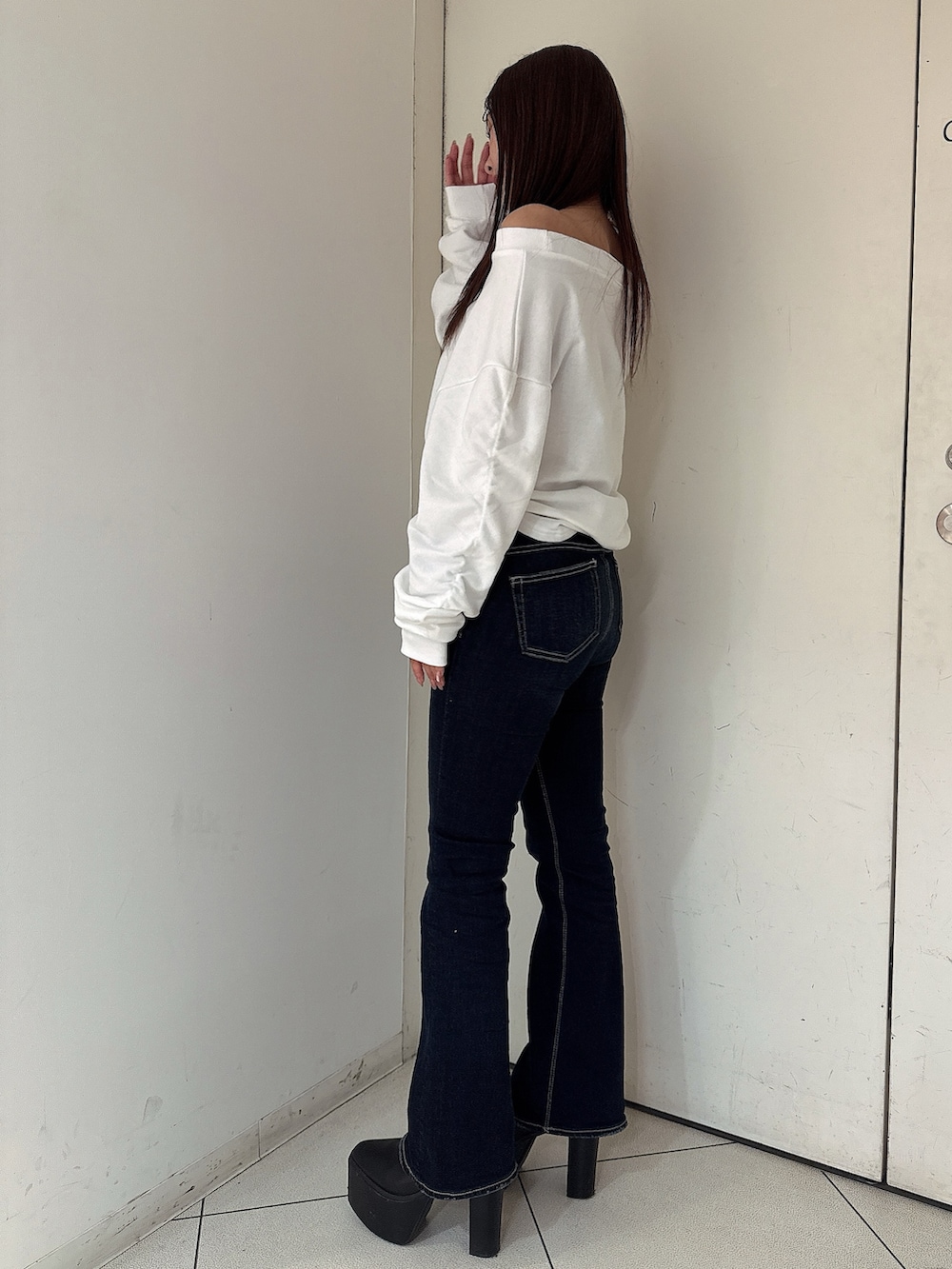 ブルー系のデニムパンツ、ブラック系のブーツ、ホワイト系のスウェットを着用したレディースの秋コーディネートの2枚目の写真