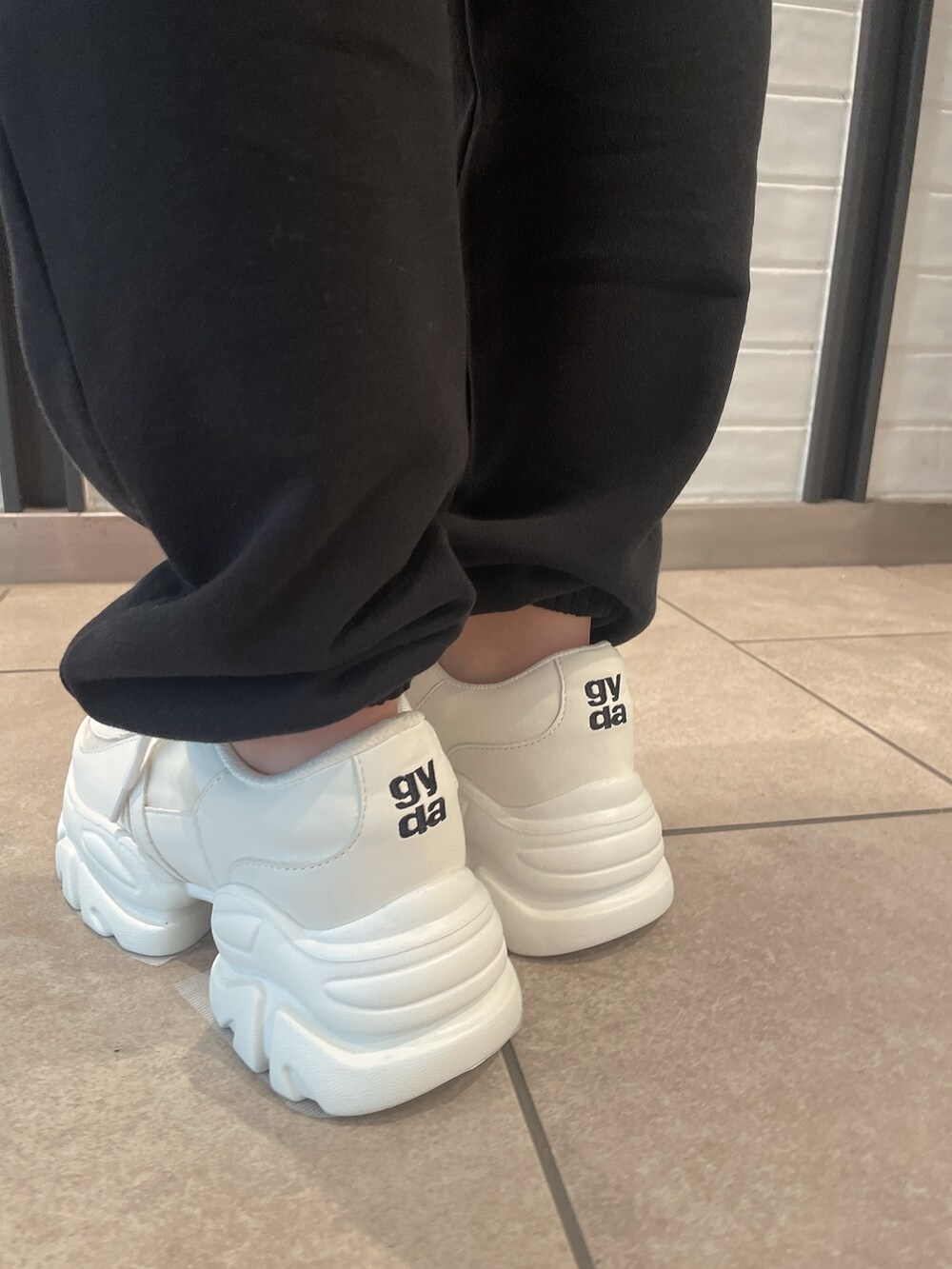 レッド系のTシャツ/カットソー、ブラック系のスウェットパンツ、ホワイト系のスニーカーを着用したレディースの夏コーディネートの9枚目の写真