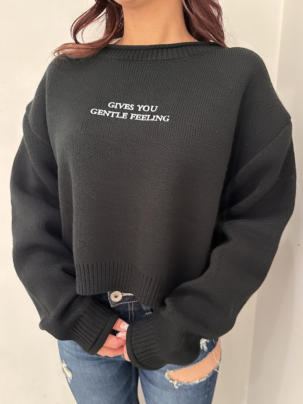 ブラック系のニット/セーター、ブルー系のデニムパンツ、ブラック系のブーツを着用したレディースの秋コーディネートの7枚目の写真