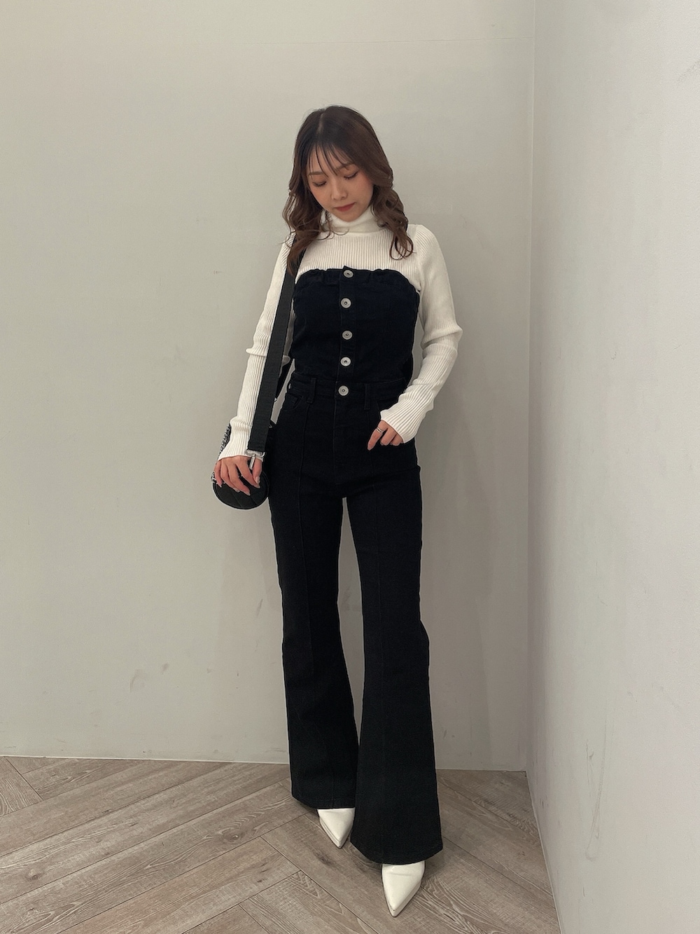 ホワイト系のニット/セーター、ブラック系のサロペット/オーバーオール、ブラック系のハンドバッグを着用したレディースの冬コーディネートの2枚目の写真