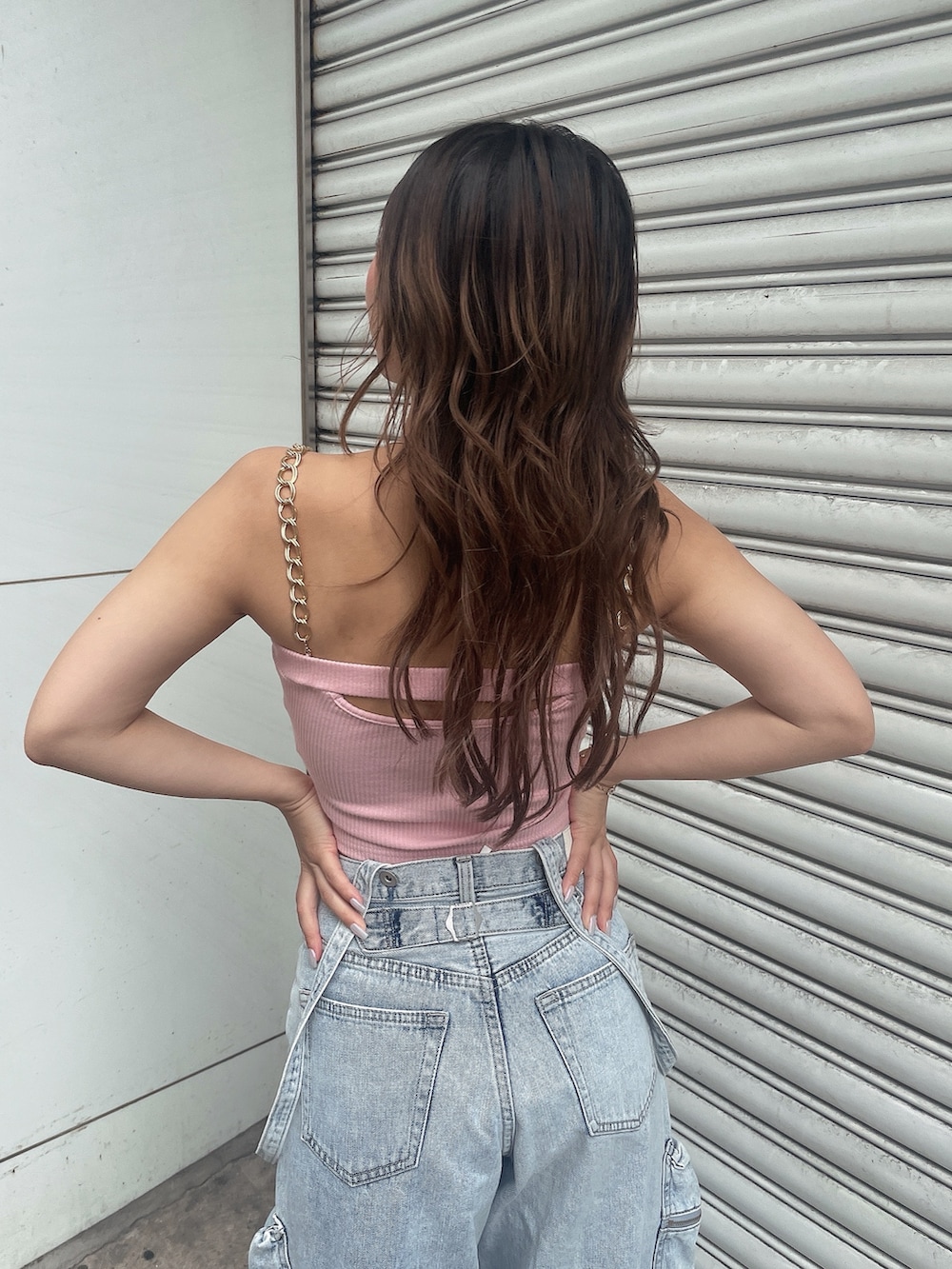 ピンク系のキャミソール、ブルー系のデニムパンツ、ホワイト系のスニーカーを着用したレディースの夏コーディネートの6枚目の写真