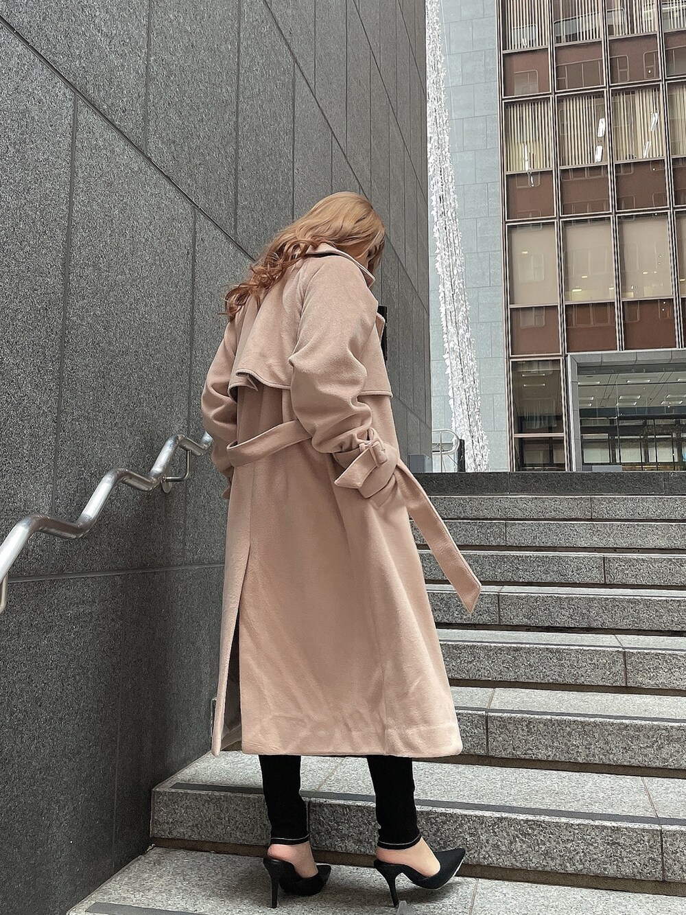 ブラック系のニット/セーター、ベージュ系のトレンチコート、ブラック系のデニムパンツを着用したレディースの冬コーディネートの3枚目の写真