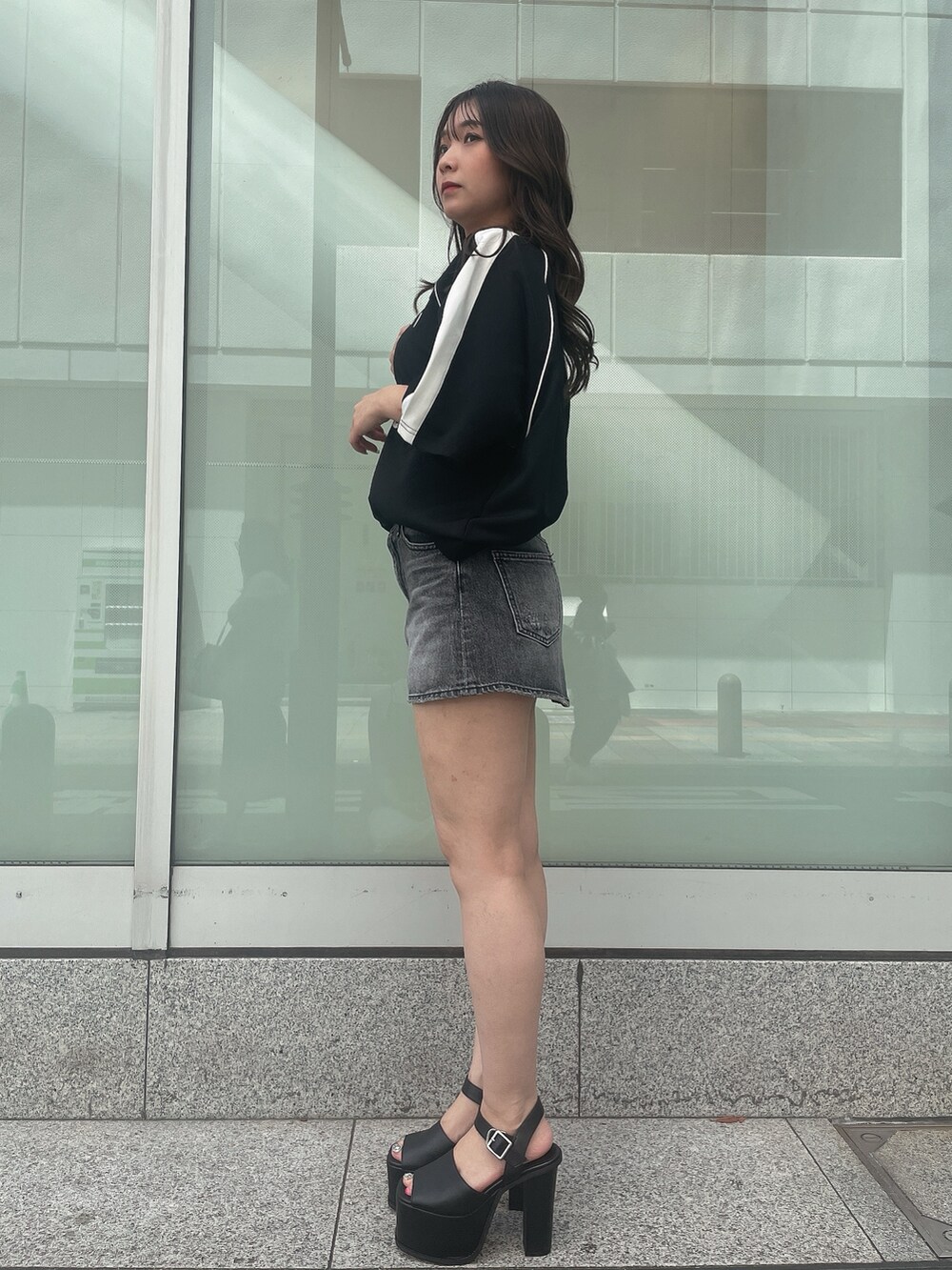 ブラック系のデニムスカート、ブラック系のTシャツ/カットソー、ブラック系のサンダルを着用したレディースの夏コーディネートの2枚目の写真