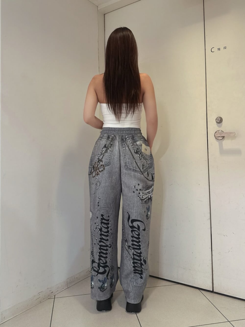 ブラック系のサンダル、ブラック系のデニムパンツ、ホワイト系のチューブトップを着用したレディースの夏コーディネートの3枚目の写真