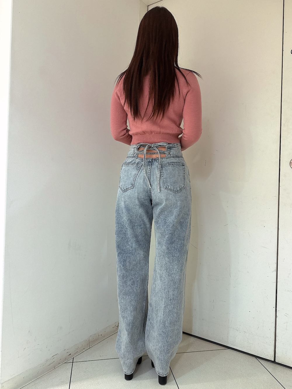 ブルー系のデニムパンツ、ピンク系のニット/セーター、ブラック系のブーツを着用したレディースの冬コーディネートの3枚目の写真